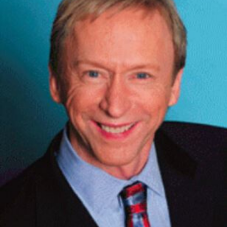 Portrait of Rev. Michael Benson wearing a suit with a blue background