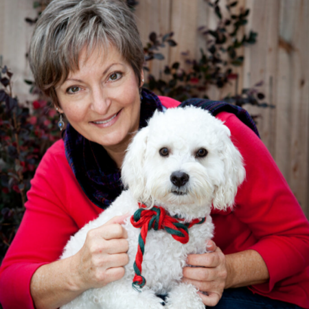 Portrait of Rev Christine Jeffers wearing a red coat with her dog